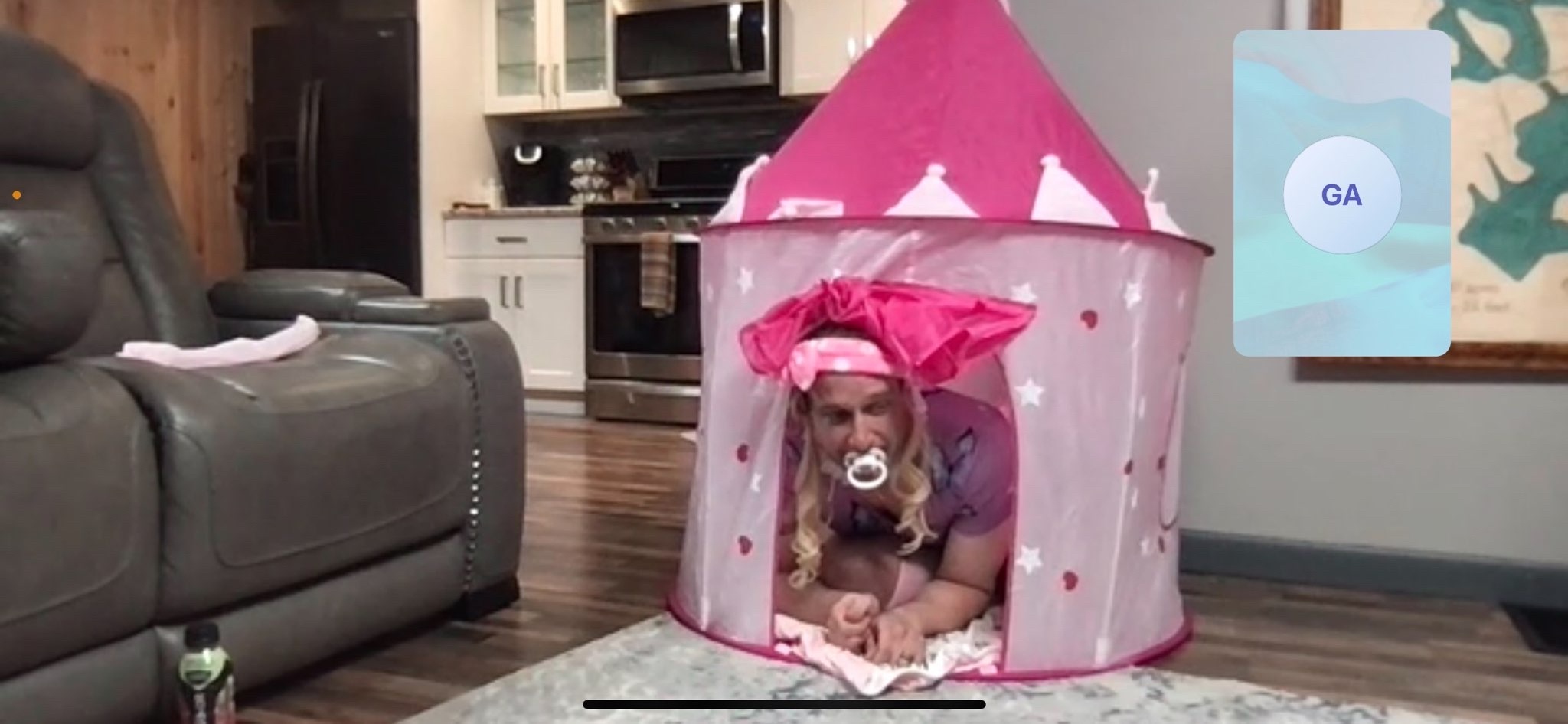 A person crouches inside a pink castle-style play tent on a rug in a living room.